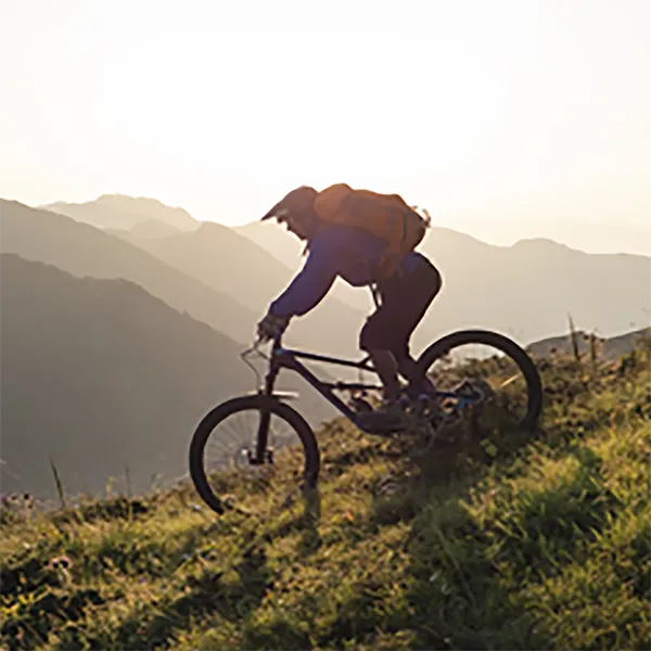 A person cycling down a grassy mountain.