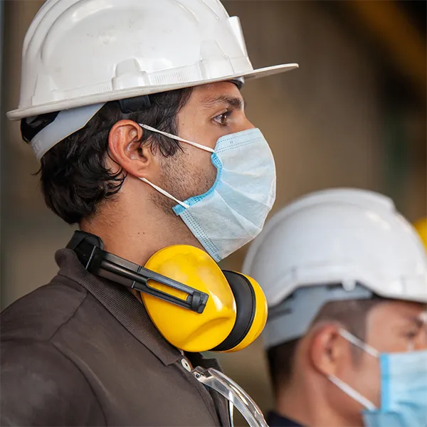 A line of construction workers wearing hard hats and masks.