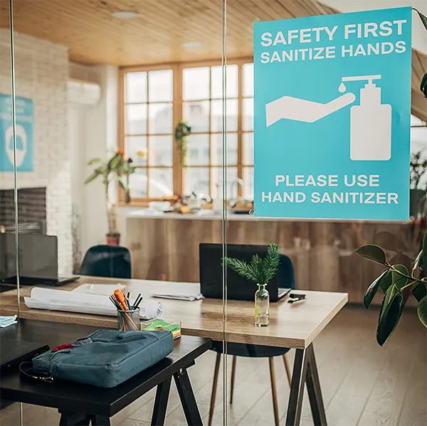 A glass door in an office with a sign promoting hand sanitizer.
