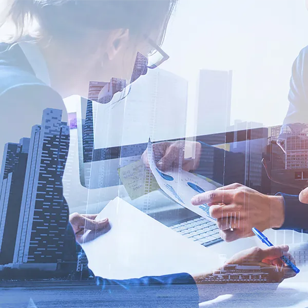 A double exposure of a city skyline with a group of professionals reviewing reports.