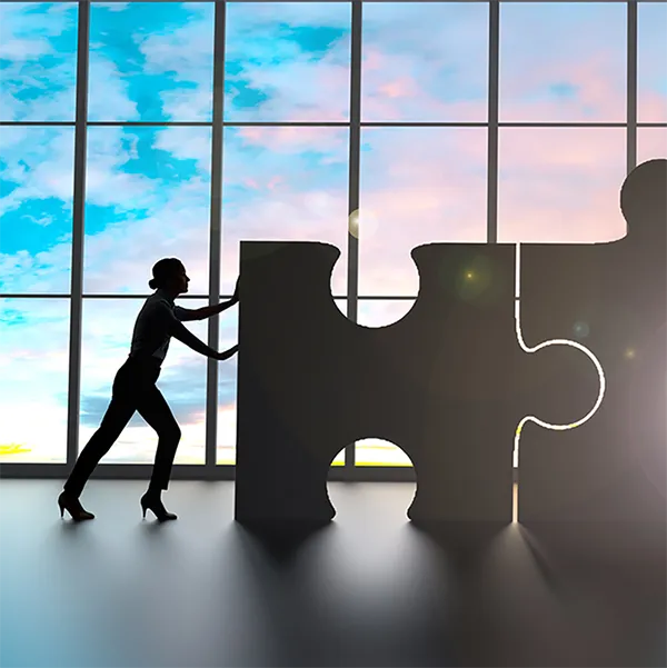 Two professionals pushing enormous puzzle pieces together.