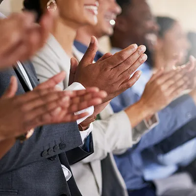 A row of people smiling and clapping.
