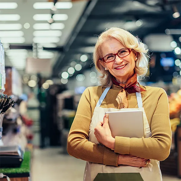A small business owner wearing an apron and holding a tablet computer.