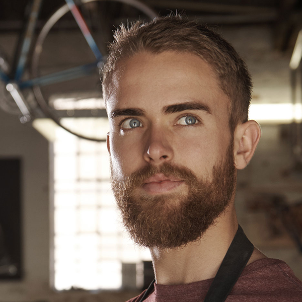 Close up of a bike shop owner looking pensively away from the camera.