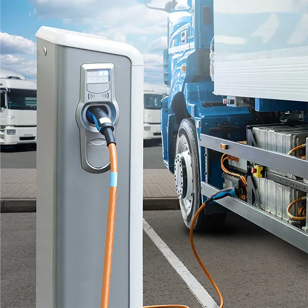 An electric big rig vehicle plugged into a charging station.