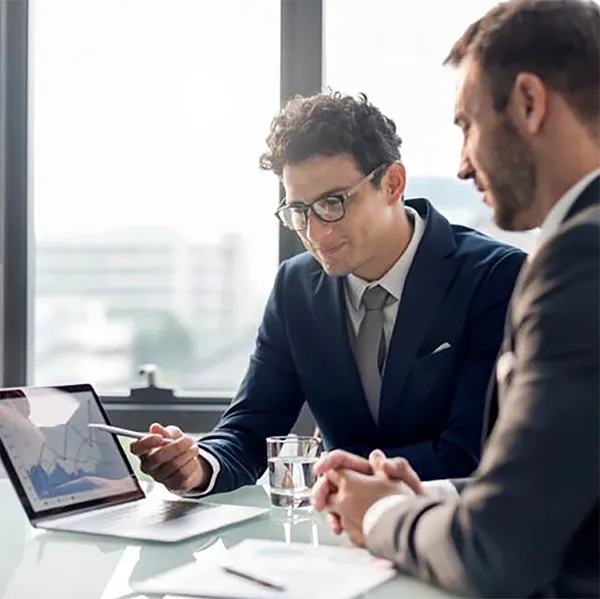 Two professionals reviewing a report on a laptop computer.