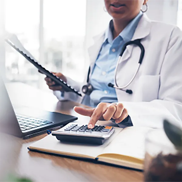 A medical professional wearing a lab coat and using a calculator.