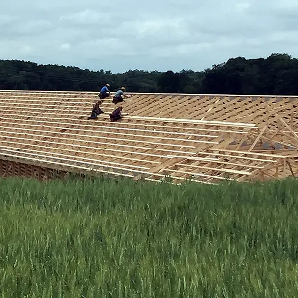 A group of construction workers working on the roof of a wooden building under construction.