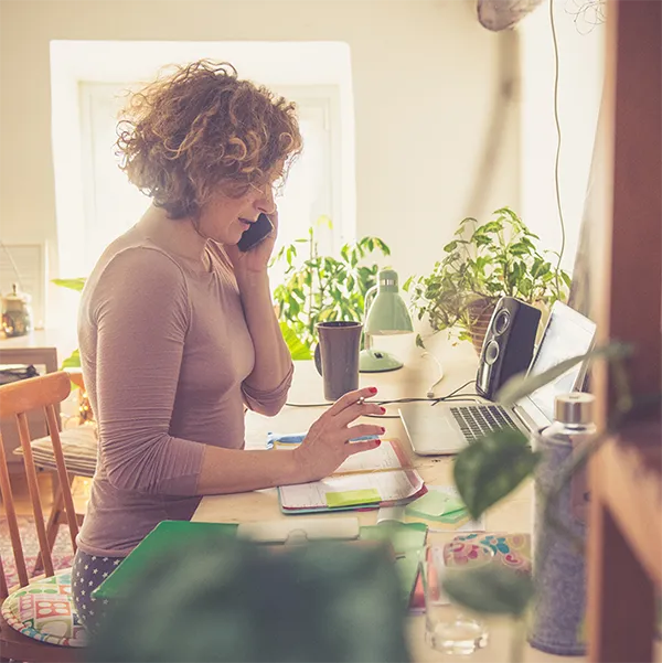 A woman speaking on the phone while working from home.