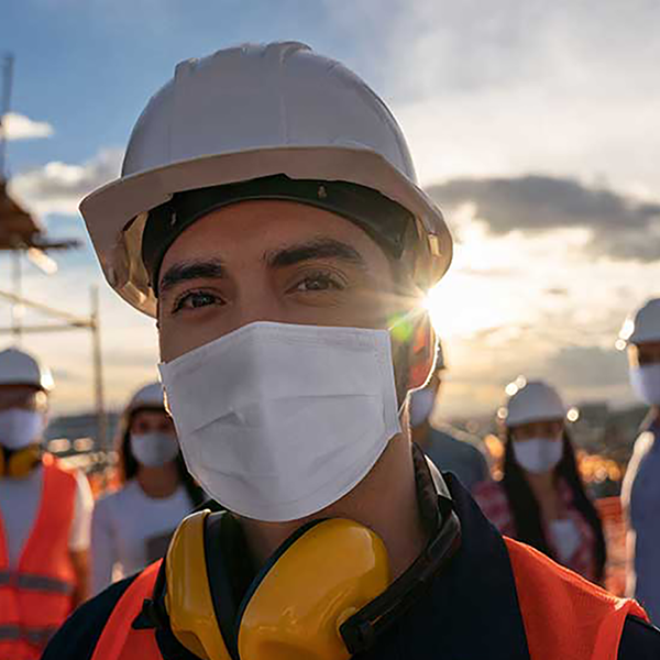 A group of construction professionals wearing safety gear and face masks.