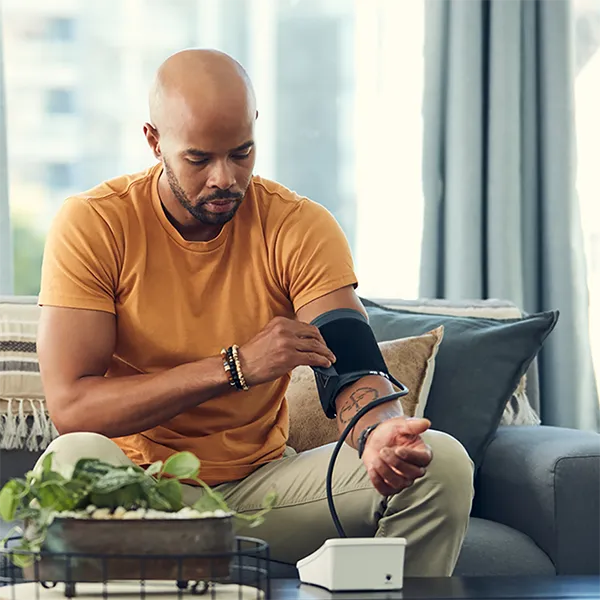 A man taking his blood pressure at home with a blood pressure cuff.