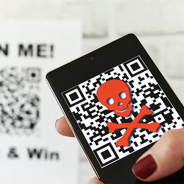 Someone scanning a QR code with their phone. The phone shows a skull and crossbones.