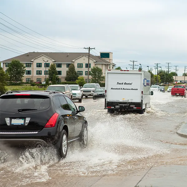 Cars driving along a flooded roadway.