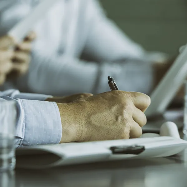 A professional wearing a button up shirt taking notes.