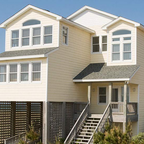 A two story yellow house by the beach.