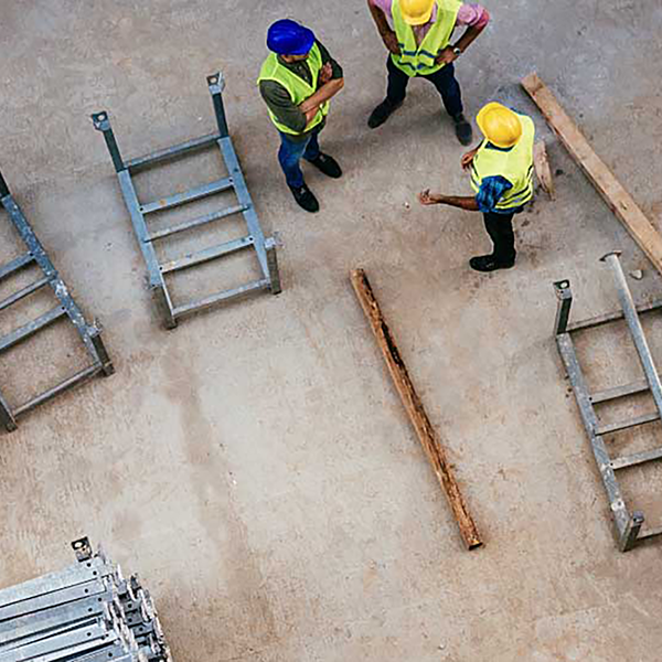 Construction workers standing next to tools and pieces of metal.