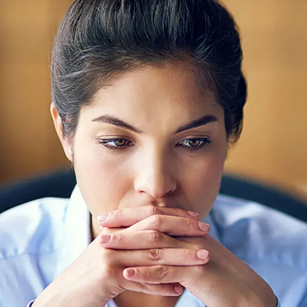 A professional sitting with their hands folded looking pensive.