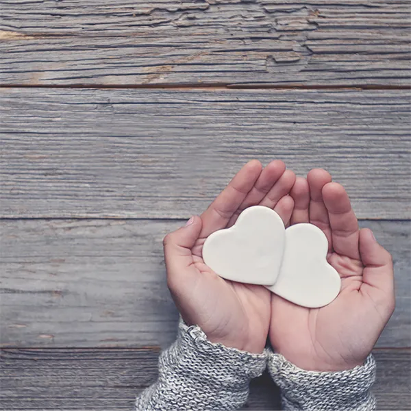A pair of cupped hands holding two ceramic hearts.