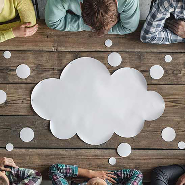 A group of professionals surrounding a table with a paper thought bubble in the middle.