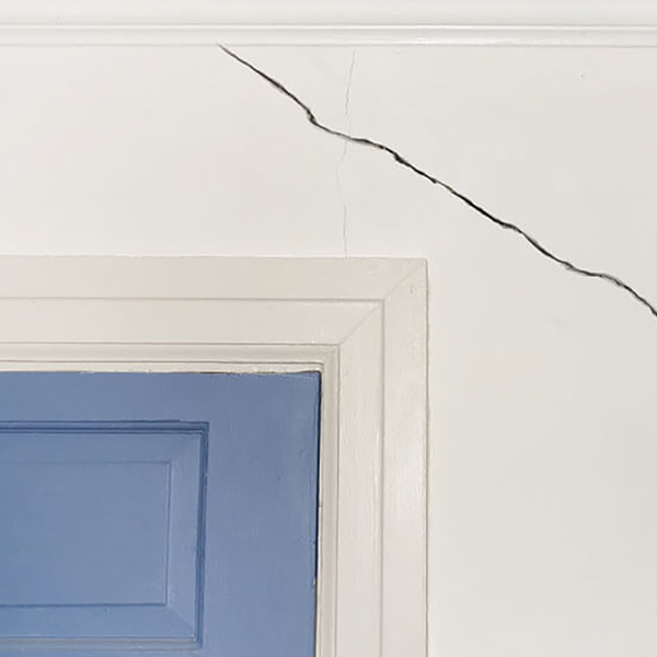A large crack above a door in a home.