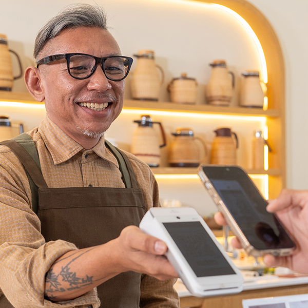 A business owner holding out a payment device for someone to pay with their phone.