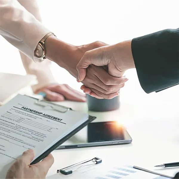 Two professionals shaking hands over a partnership agreement.
