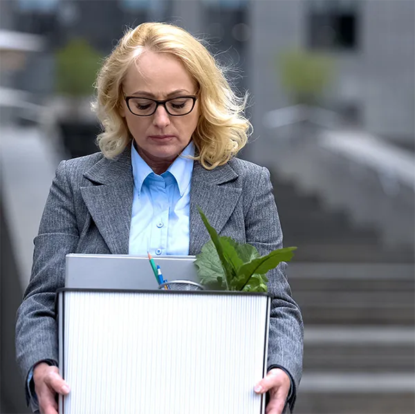 A professional holding a box with supplies from her desk.