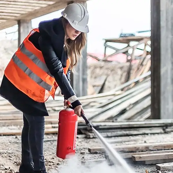 A person wearing an orange vest using a fire hydrant on a construction site.
