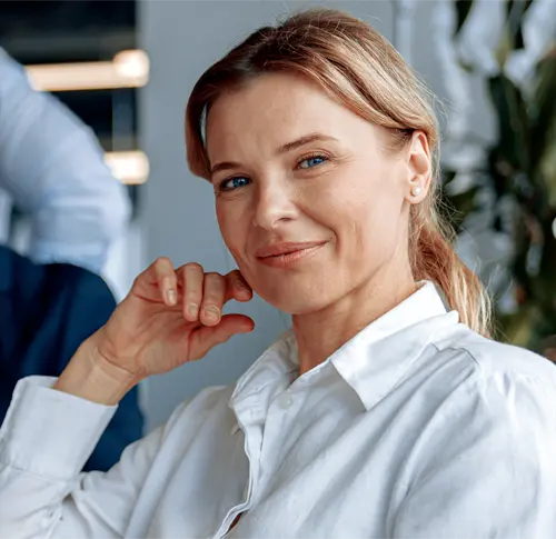 A business woman sitting with a group and and looking at the viewer.