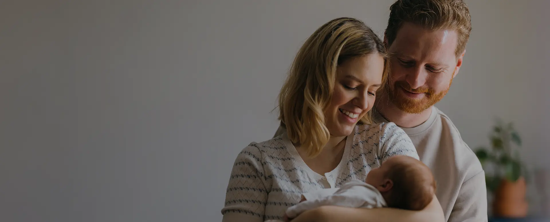 A man & woman smiling at a baby being held in the woman's arms.