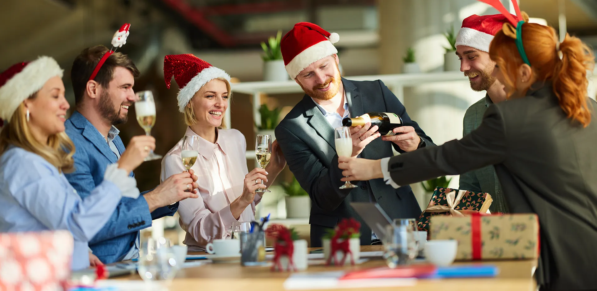 A group of office workers wearing holiday garb and toasting with champagne.