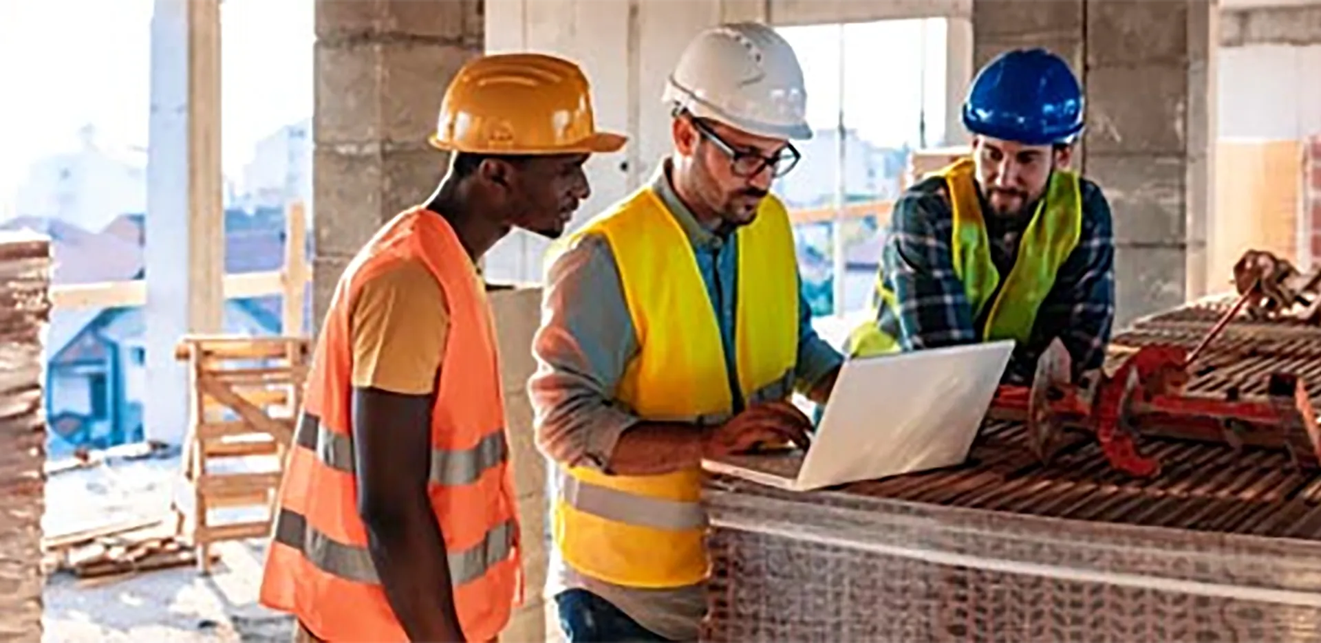 Three contractors looking at a laptop computer.