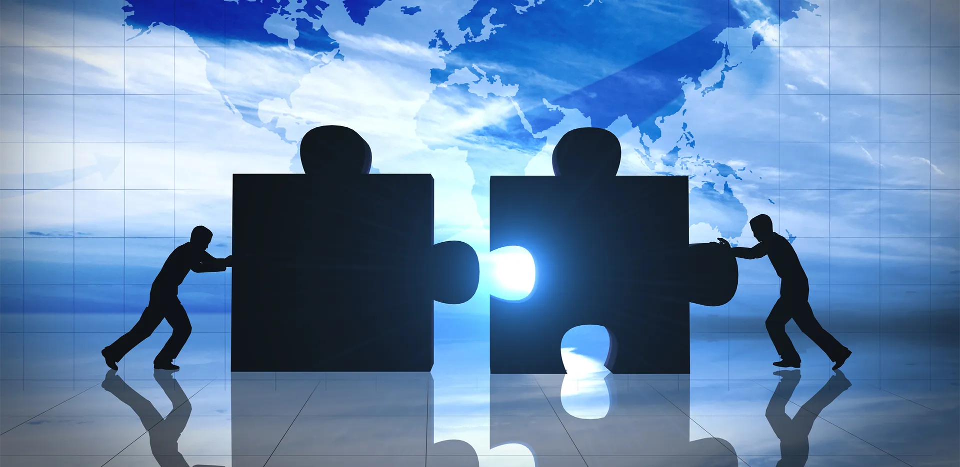 Two people push large puzzle pieces together.