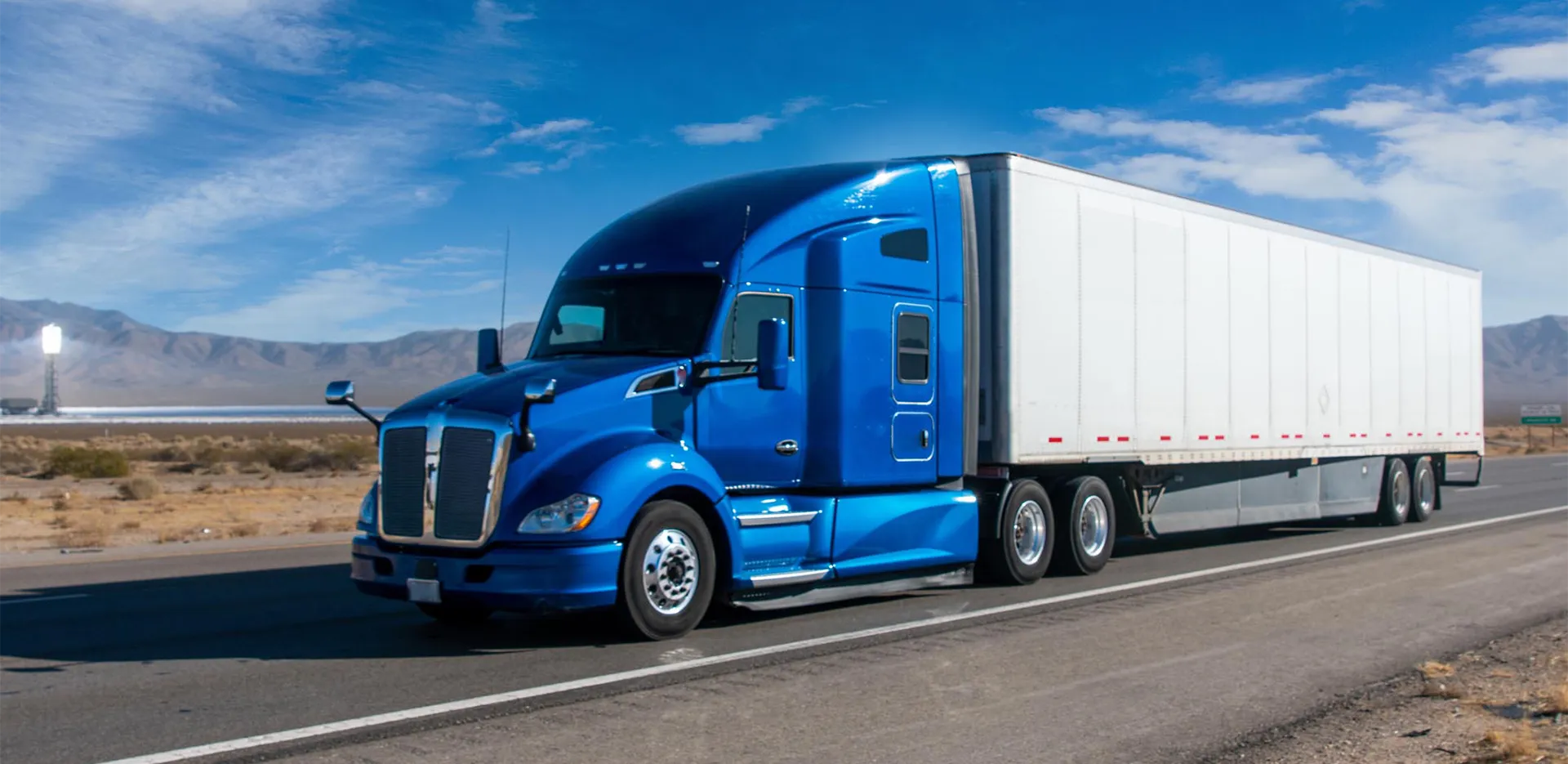 A semi truck with a blue cab on the highway.