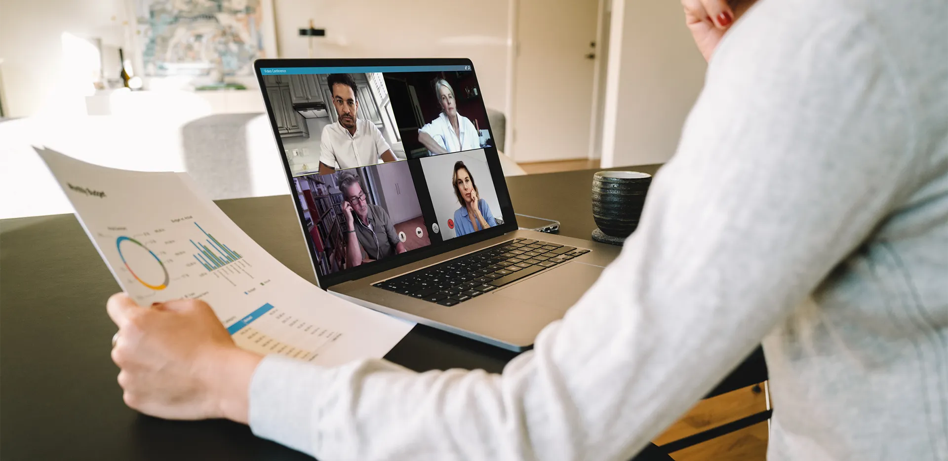 A woman reading a report while participating in a video conference.