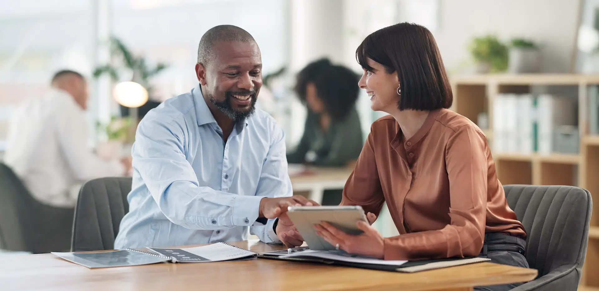 Two professionals discussing business insurance while looking at a tablet.