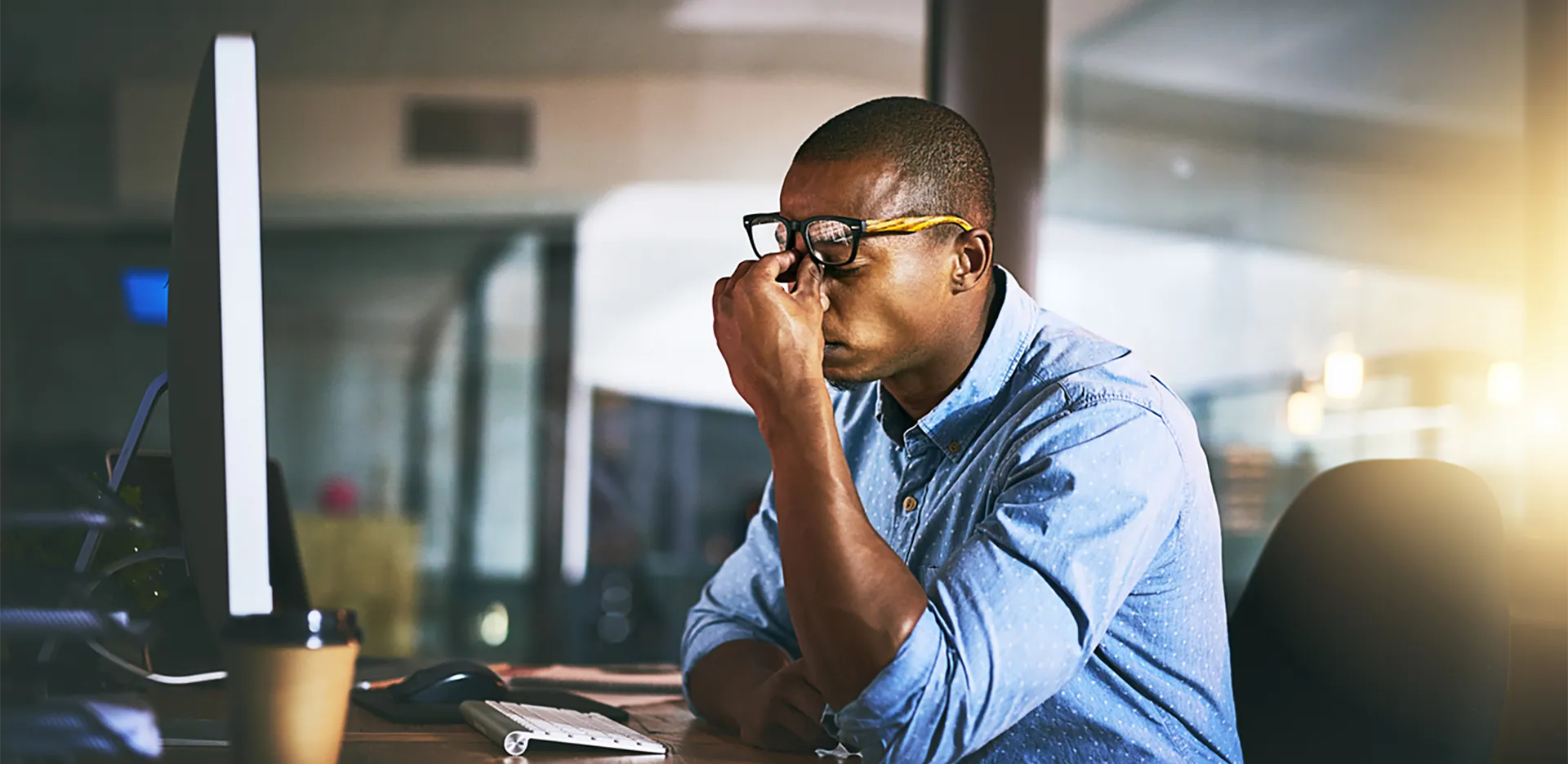 A professional at a computer pinching their forehead in stress.
