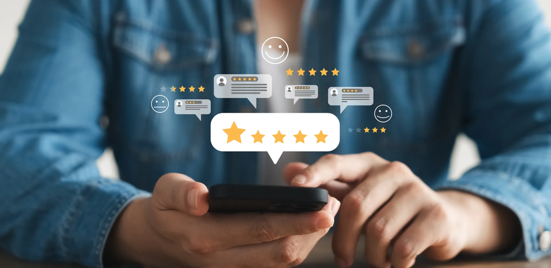 A person holding a phone in their hands with chat bubbles and emojis floating above the phone.