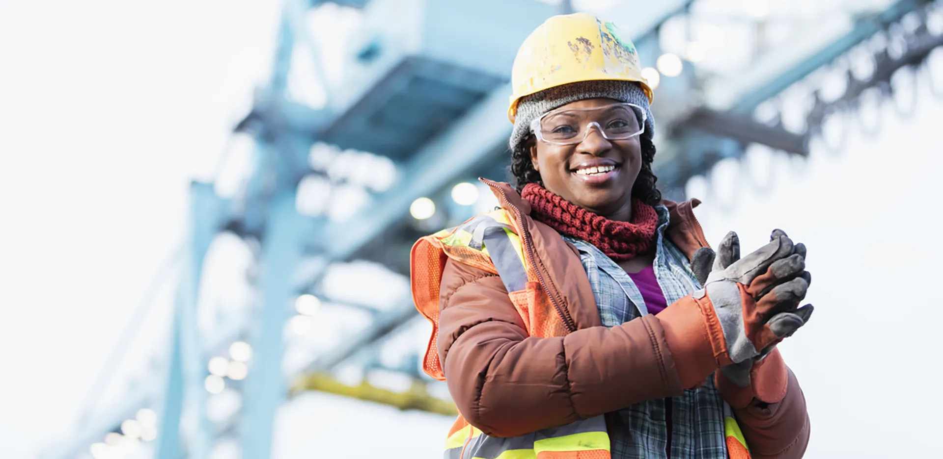 A construction worker dressed for winter weather wearing a hard hat and gloves.