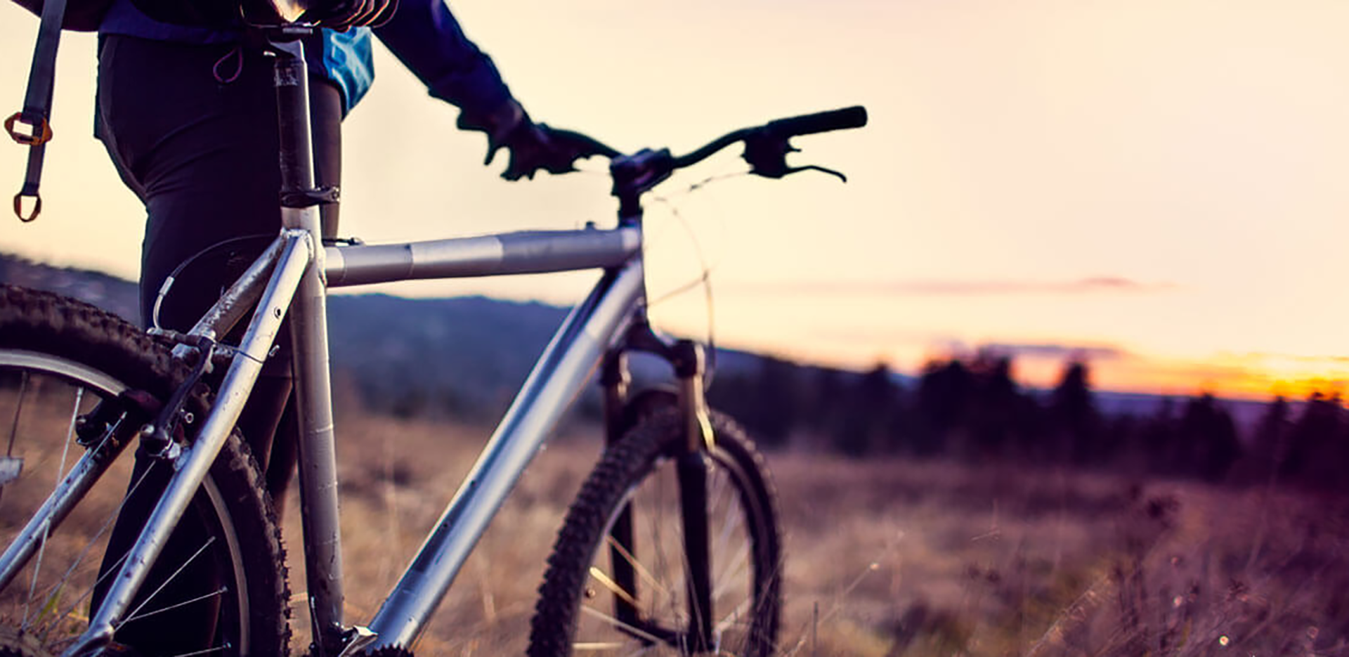 A person standing with their mountain bike.