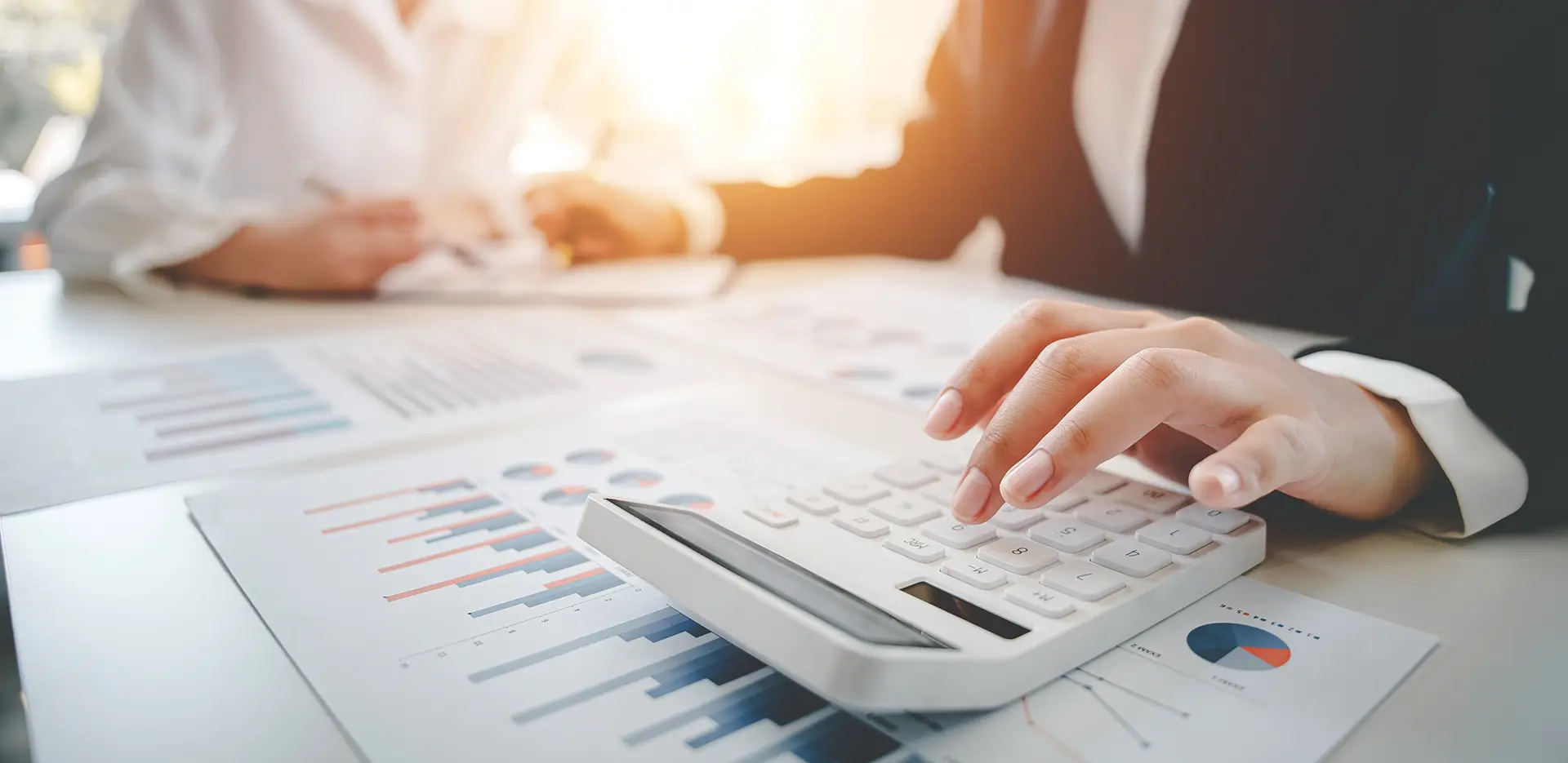 Two professionals looking at report data and using a calculator.