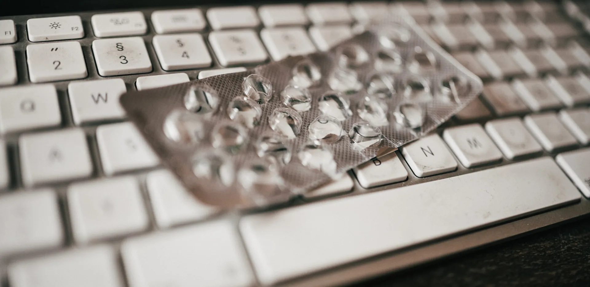An empty pill blister pack sitting on top of a computer keyboard.
