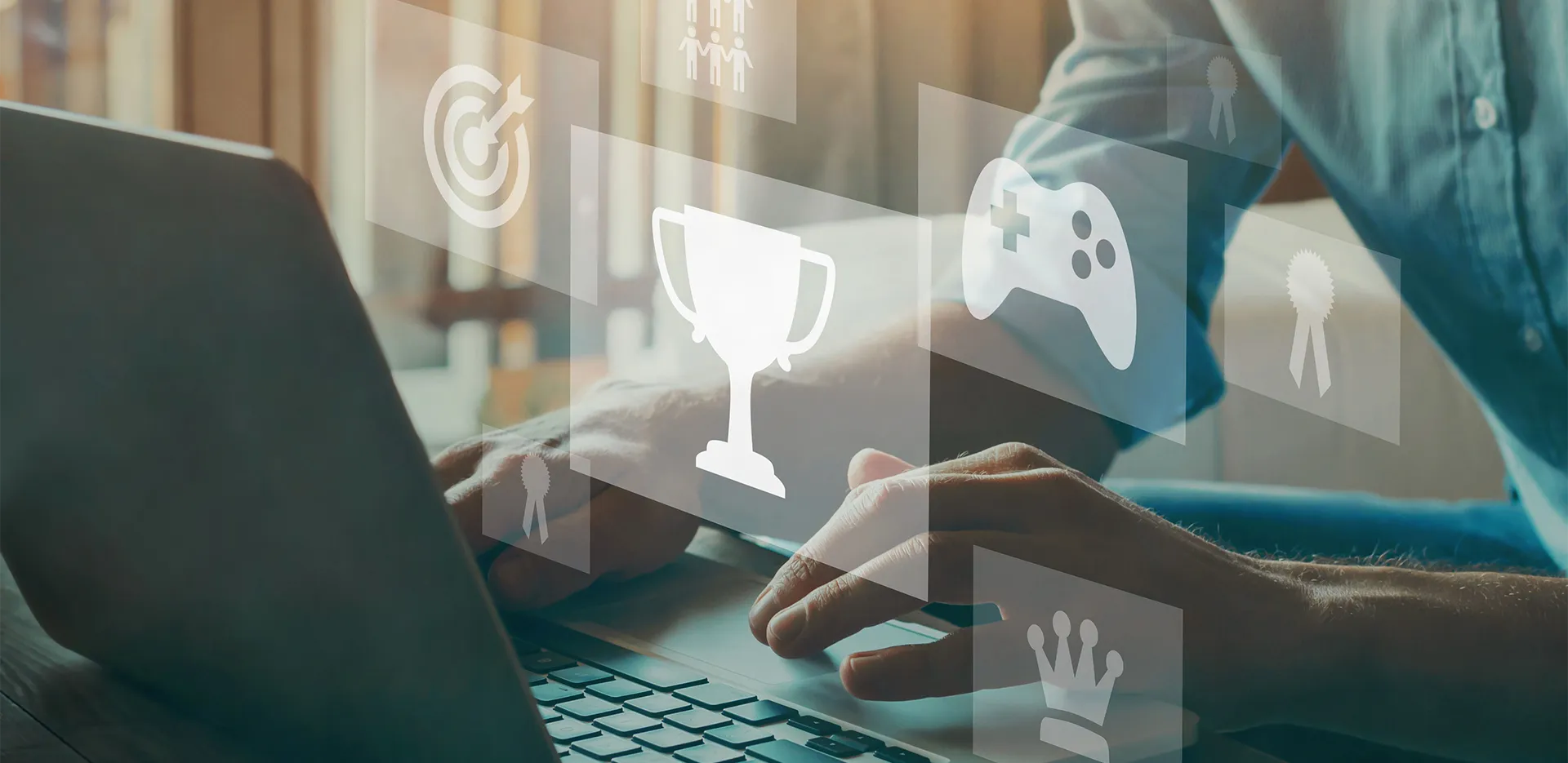 A persons hands on a laptop with gaming icon images floating above in the air.