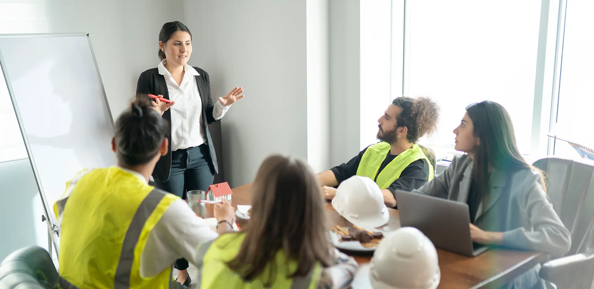 A safety meeting with workers in yellow vests sitting at a table