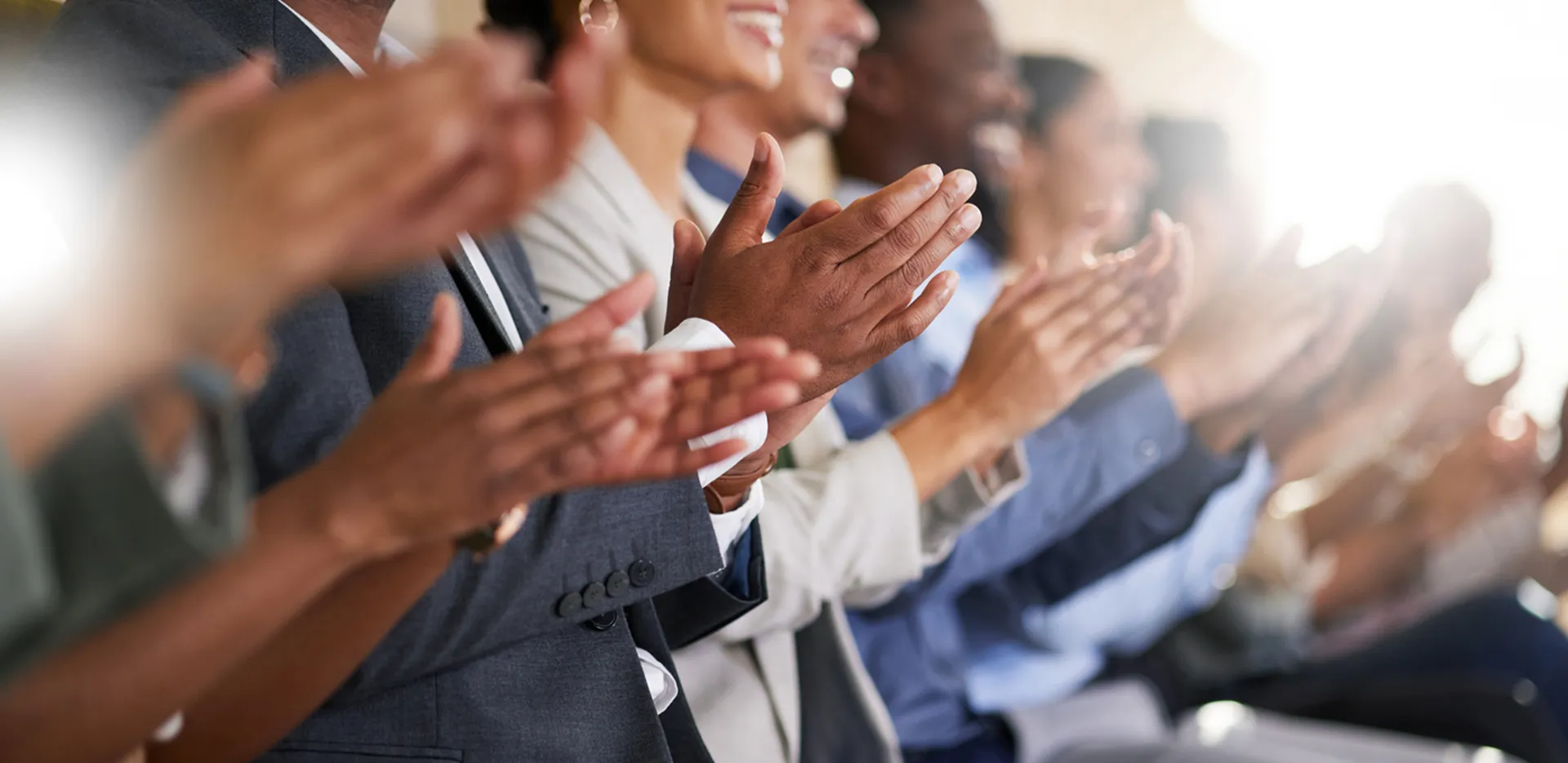 A row of people smiling and clapping.