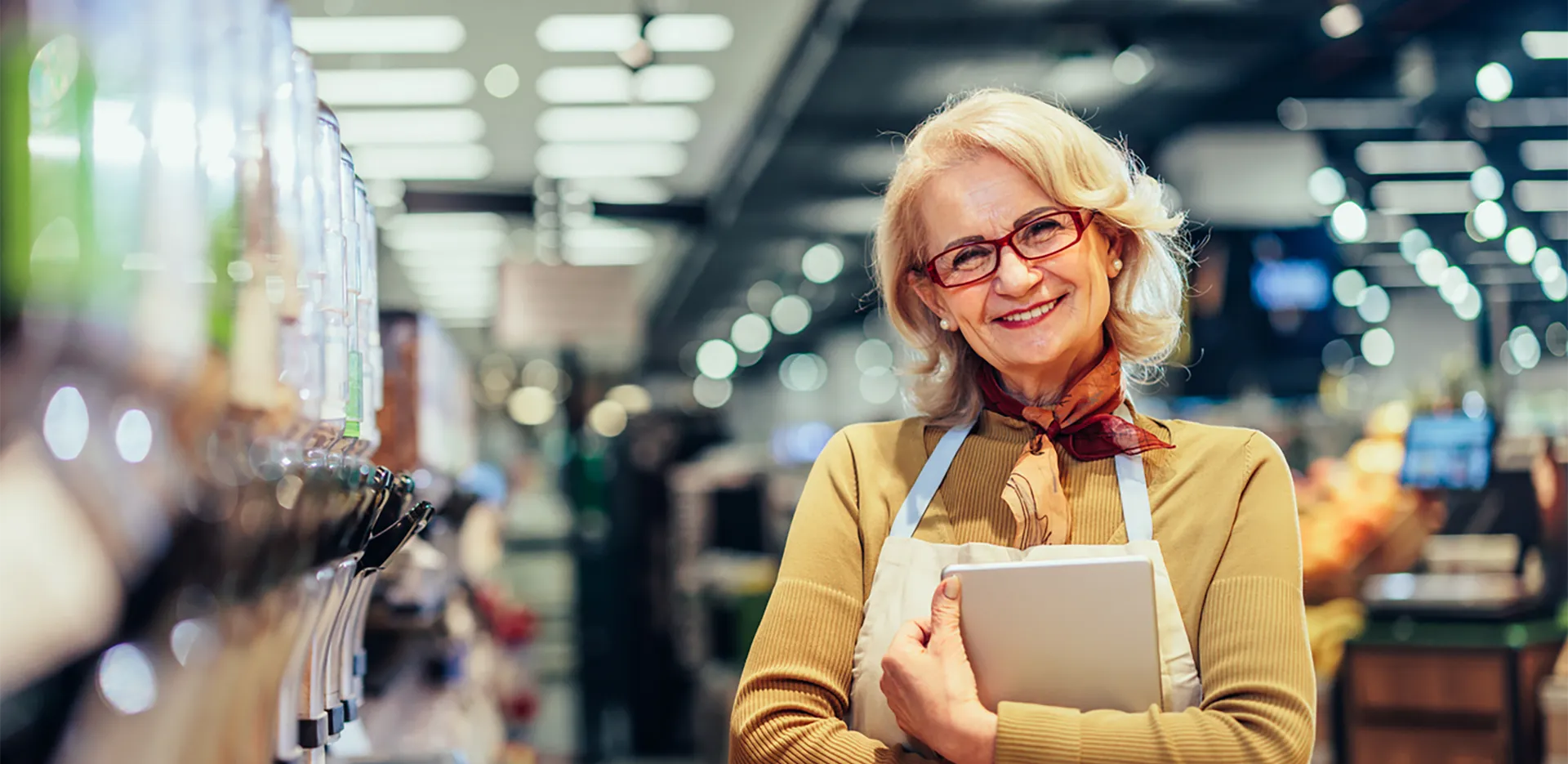 A small business owner wearing an apron and holding a tablet computer.