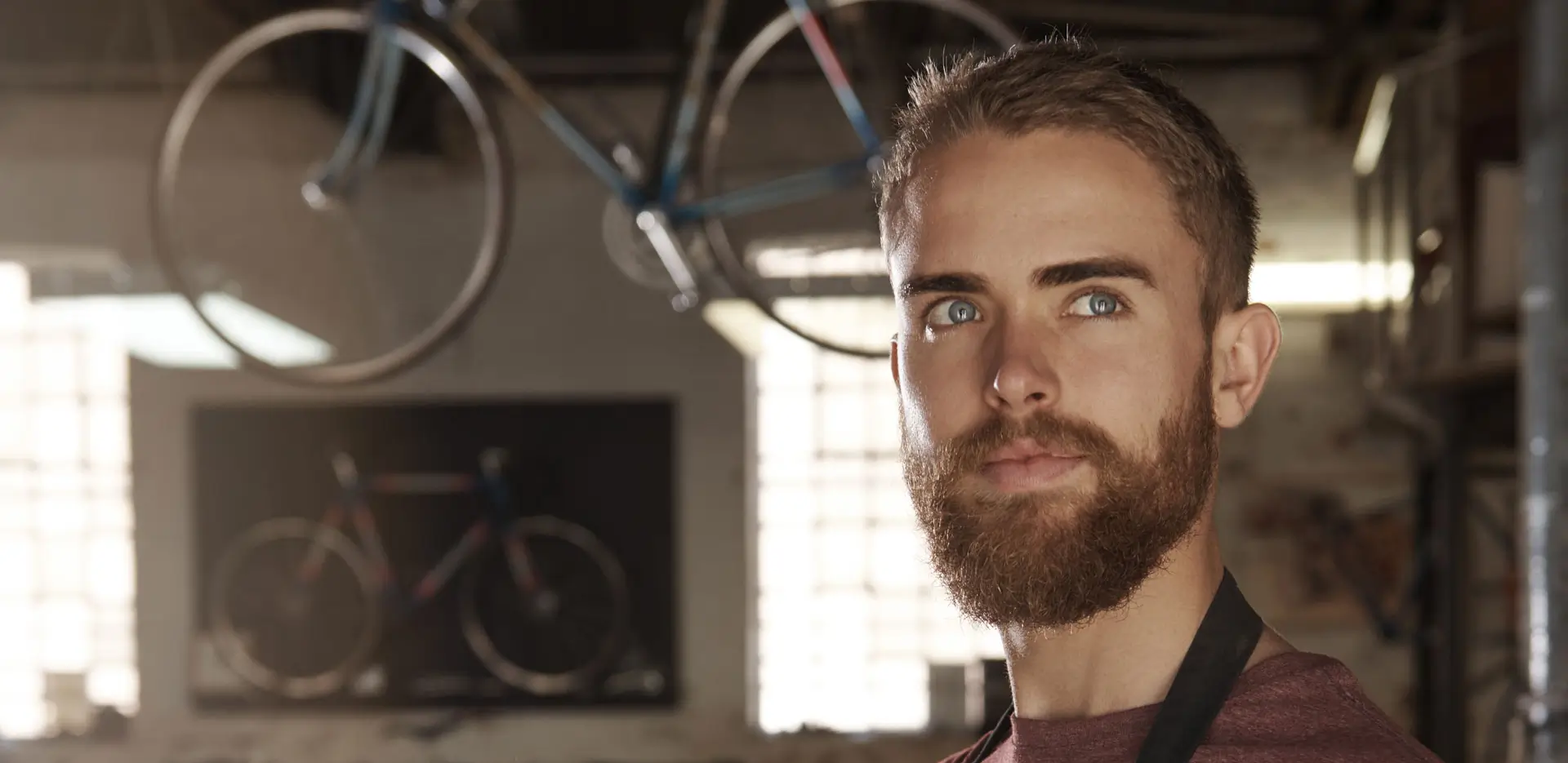Close up of a bike shop owner looking pensively away from the camera.