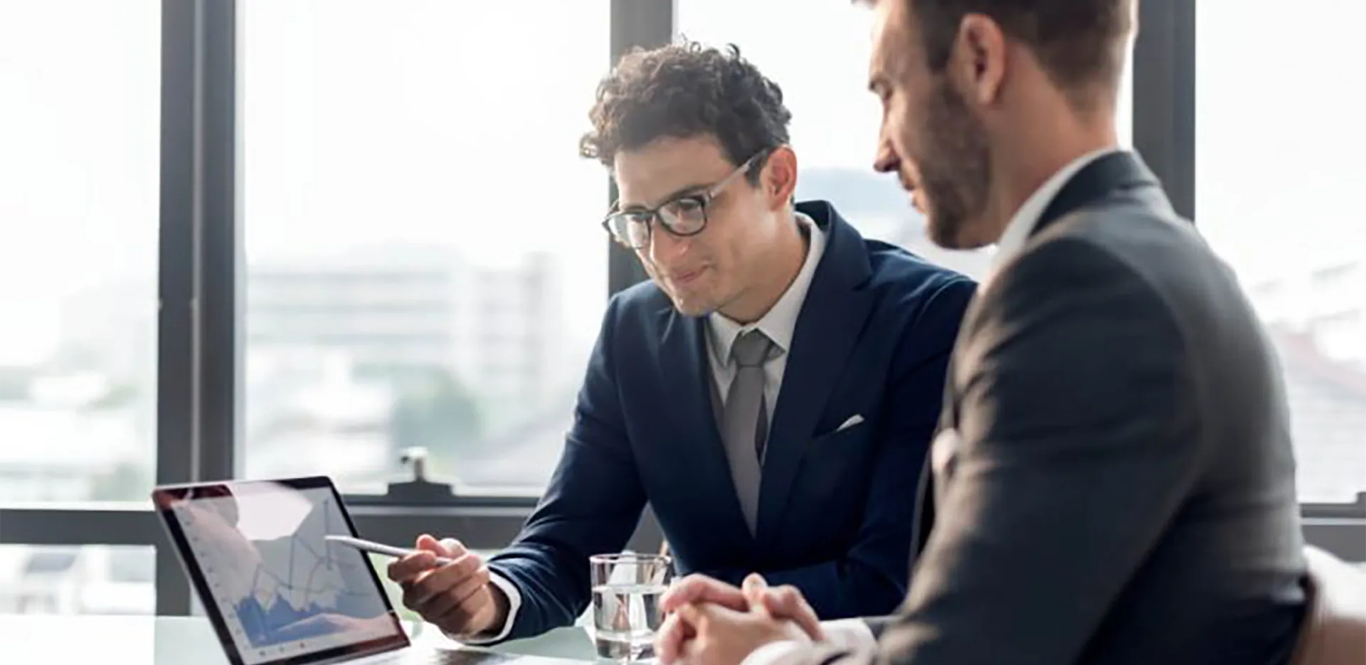 Two professionals reviewing a report on a laptop computer.