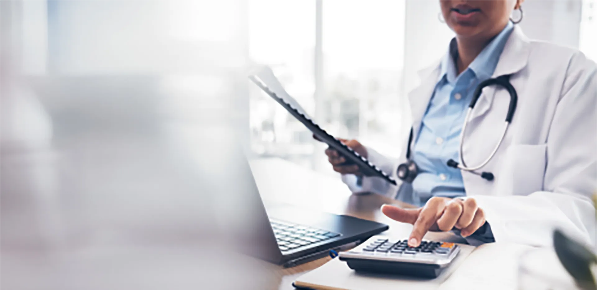 A medical professional wearing a lab coat and using a calculator.