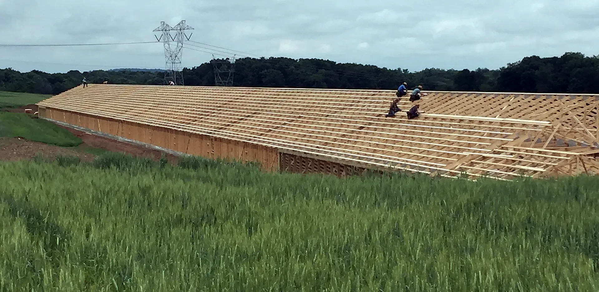 A group of construction workers working on the roof of a wooden building under construction.
